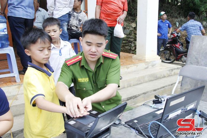 Đoàn viên chi đoàn Công an phường Chiềng Cơi thu nhận hồ sơ cấp định danh điện tử cho trẻ em ở bản San.