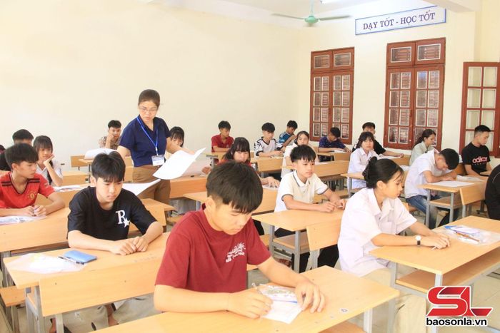 Giám thị phát giấy thi cho thí sinh.