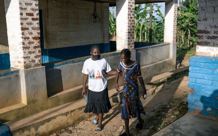 Một người phụ nữ không đeo găng tay đỡ em gái mình, người bị nghi nhiễm Ebola, tại Bệnh viện Đa khoa Mongbwalu. Ảnh: The New York Times