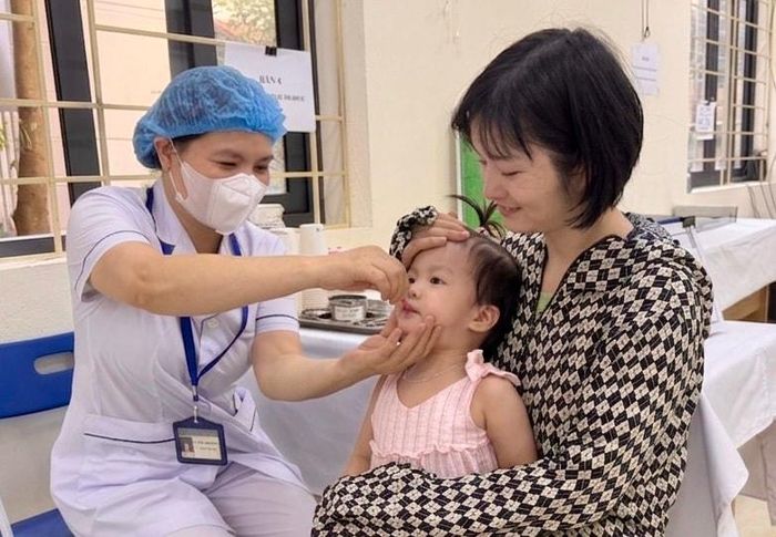 Cán bộ Trạm Y tế phường Ô Chợ Dừa cho trẻ uống Vitamin A. Ảnh: Võ Giang