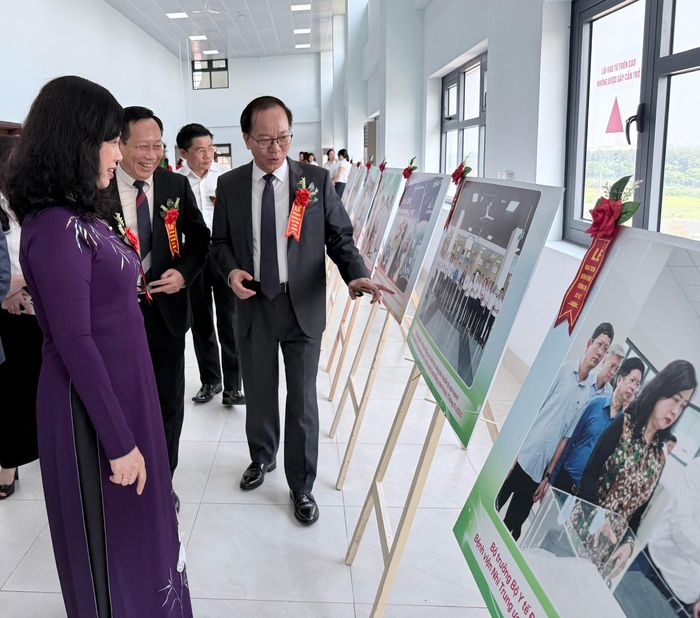 Bộ trưởng Đào Hồng Lan nghe GS.TS Trần Minh Điển - Giám đốc Bệnh viện Nhi Trung ương giới thiệu triển lãm ảnh về quá trình xây dựng, hoàn thiện Cơ sở 2 trưng bày bên lễ sự kiện.
