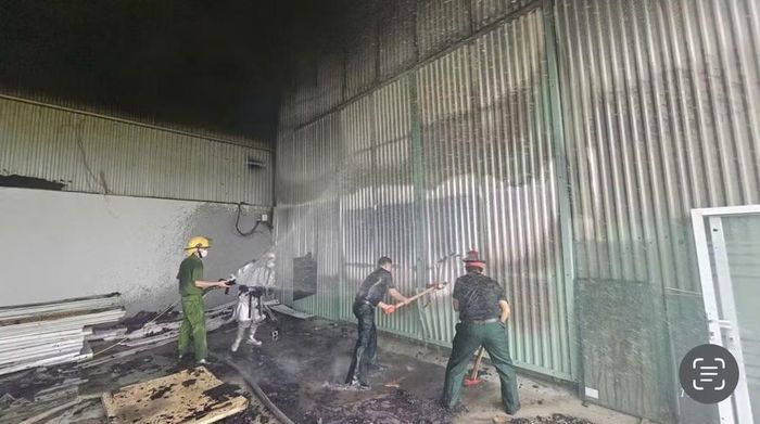 Lực lượng chức năng phá tường tôn dập lửa.