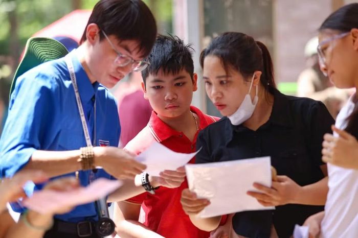 Sinh viên tình nguyện hỗ trợ thí sinh và phụ huynh tra cứu thông tin phòng thi trước giờ làm bài. (Ảnh: THANH TÙNG)
