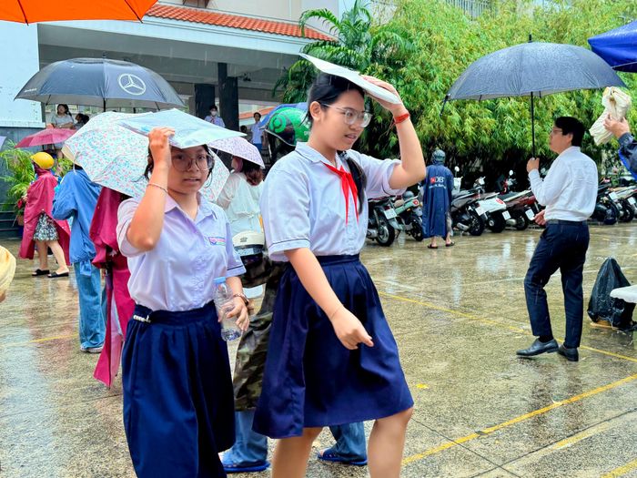  Thí sinh dùng tập hồ sơ che mưa khi rời phòng thi sau khi hoàn thành kỳ thi tuyển sinh lớp 10 tại Trường THPT Nguyễn Hữu Thọ, phường Xóm Chiếu (TPHCM) ẢNH: HOÀNG HÙNG 