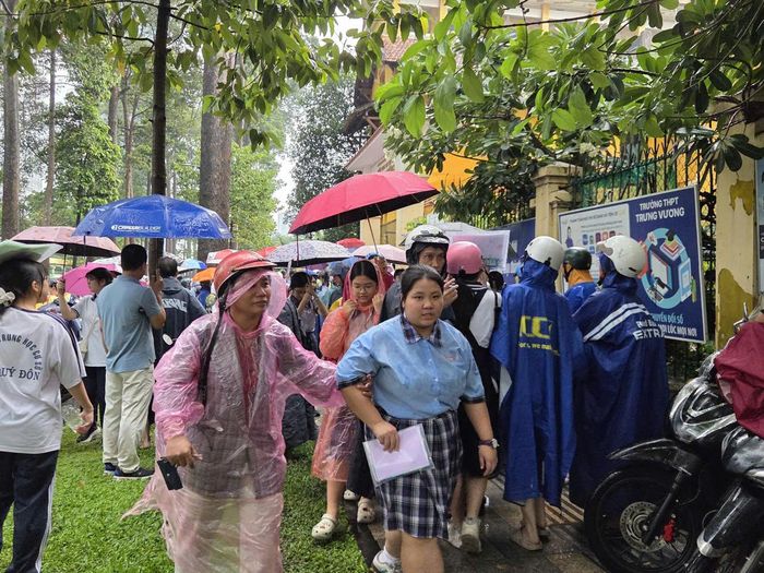  Phụ huynh chờ đón con dưới cơn mưa tầm tã tại điểm thi THPT Trưng Vương. Ảnh: THU TÂM. 