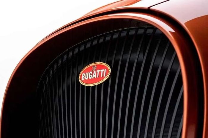 Khu vực đầu xe Bugatti W16 Mistral Le Retour du Jeune Prince vẫn duy trì lưới tản nhiệt hình móng ngựa truyền thống của thương hiệu nhưng các nan bên trong được định hình theo dạng dọc, kết hợp cùng logo macaron Bugatti mạ vàng sang trọng.