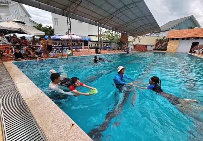 Giáo viên hướng dẫn các em học sinh tập bơi.