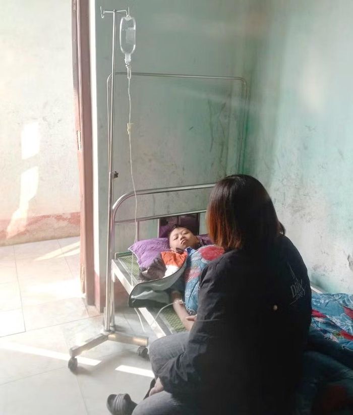 Cô Lộc Thị Lưu - nhân viên y tế Trường PTDTBT THCS Tả Ván trong một lần đưa học sinh đến khám tại trạm y tế xã và chăm sóc nam sinh khi phụ huynh chưa đến kịp.