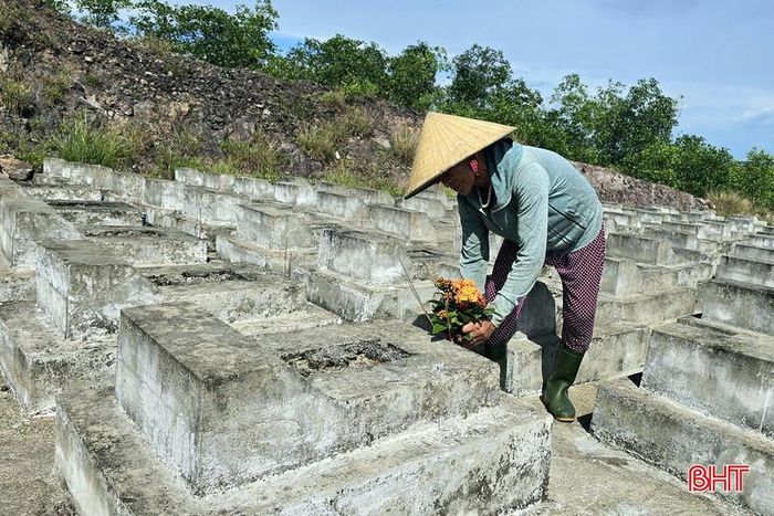Một hội viên người cao tuổi đặt bó hoa rừng trên phần mộ.