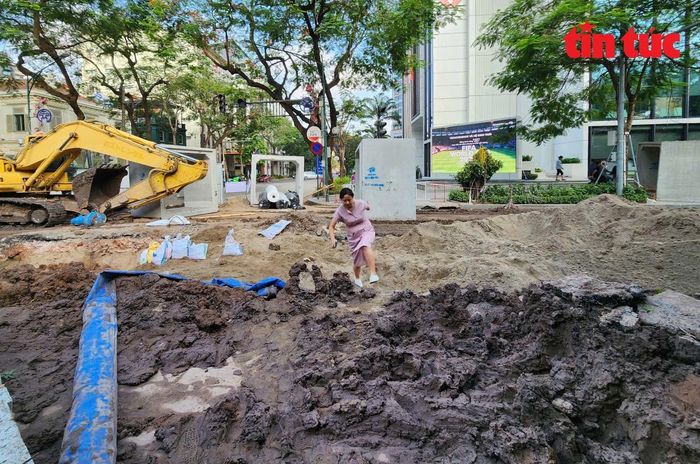 Người dân đi tắt băng qua công trường chống ngập trên đường Quang Trung.