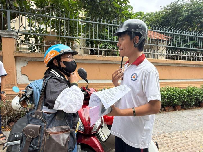 Một học sinh vui vẻ chia sẻ thông tin về môn thi Toán với mẹ.