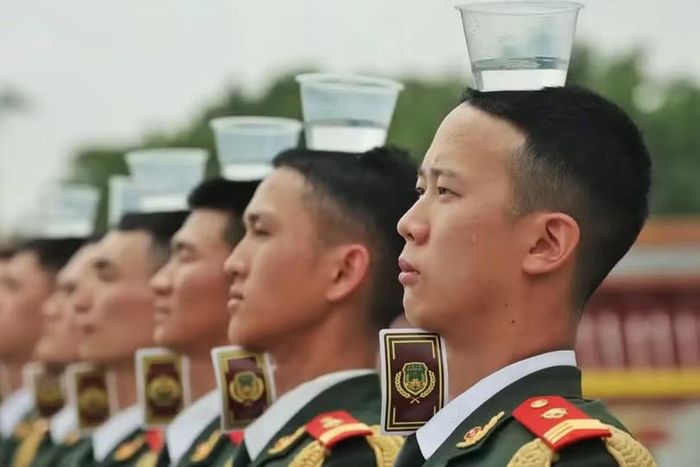 Một hàng binh sĩ nghi lễ đứng nghiêm trang với những cốc nước trên đầu trong lúc huấn luyện. Ảnh: bjd.com.