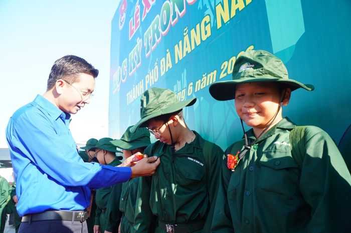 Anh Nguyễn Bá Duân, Phó Bí thư Thành đoàn, Chủ tịch Hội Liên hiệp Thanh niên Việt Nam thành phố Đà Nẵng cài hoa lên ngực các "chiến sĩ nhí" tại lễ xuất quân. Ảnh: TÂM ĐAN