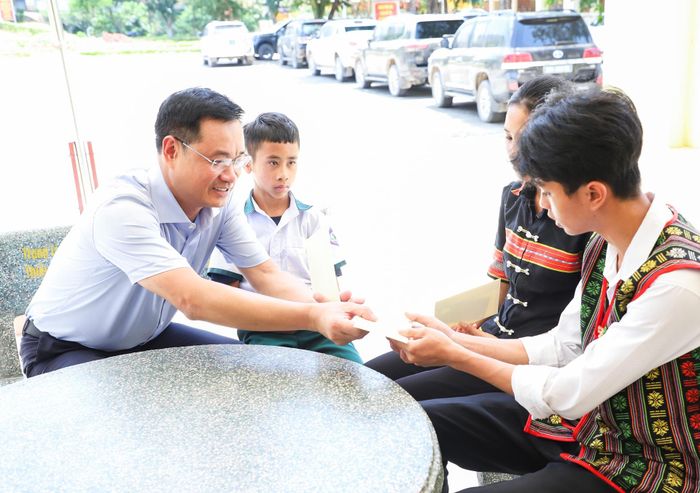 Bí thư Thành ủy Lê Ngọc Quang (bên trái) trao quà cho các em học sinh là "con nuôi" của Đồn Biên phòng Cửa khẩu quốc tế Nam Giang trong chương trình "Con nuôi biên phòng". Ảnh: NGỌC PHÚ