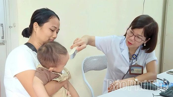 Nhân viên y tế phường khám bệnh cho trẻ em.