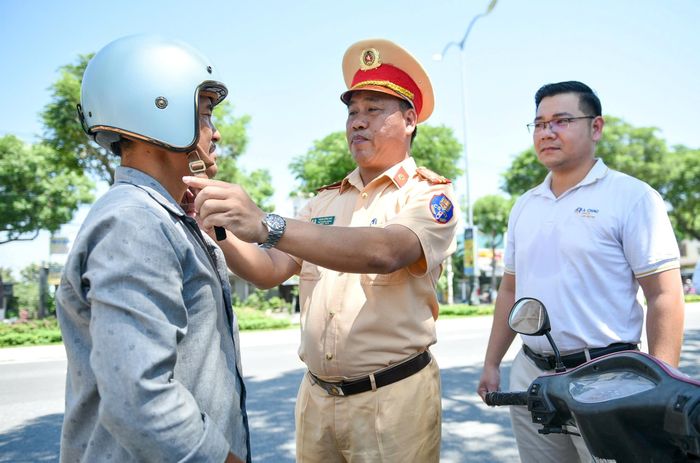 Thượng tá Phạm Hồng Hải - Phó Trưởng Phòng CSGT Công an TP Đà Nẵng và đại diện doanh nghiệp tặng mũ bảo hiểm đến người dân.