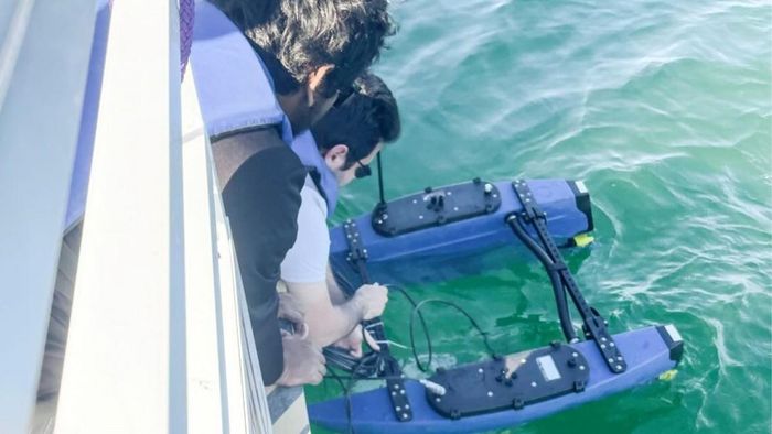 TS. Md Jahidul Islam và TS. Adam Khalifa hạ robot tự hành BlueME xuống mặt nước từ mạn tàu trong buổi thử nghiệm thực địa. Ảnh: Đại học Florida.