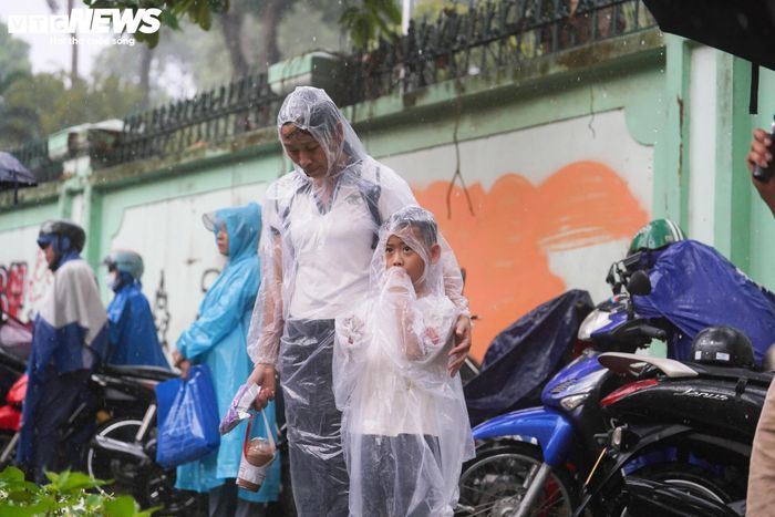 Bên ngoài các điểm thi, bất chấp thời tiết không thuận lợi, nhiều phụ huynh vẫn kiên nhẫn chờ đợi con em dưới mưa. 