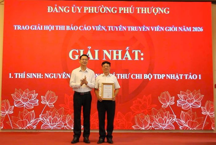 Đồng chí Trần Quang Đạo, Phó Bí thư Thường trực Đảng ủy phường Phú Thượng, Trưởng ban tổ chức Hội thi Báo cáo viên, Tuyên truyền viên giỏi năm 2026 trao giải Nhất cho thí sinh. Ảnh: Hoàng Vũ