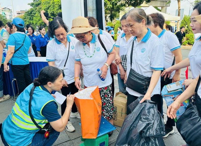 Người dân tham gia đổi giấy, rác nhựa lấy sản phẩm tái chế. Ảnh: Bảo Lâm
