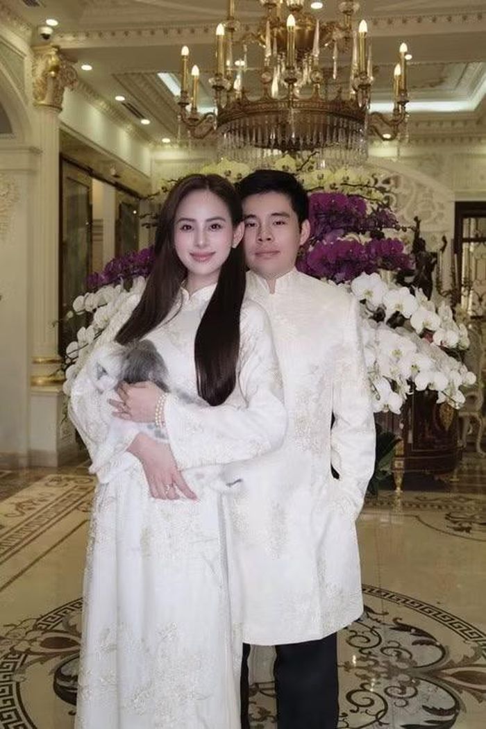 Vợ chồng Hương Liên thực hiện bộ ảnh gia đình trong không gian sang trọng. Người đẹp diện áo dài trắng nền nã, trong khi ông xã xuất hiện lịch lãm. Thú cưng cũng góp mặt như một thành viên đặc biệt của gia đình. Ảnh: Instagram Hương Liên.