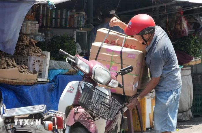 Người dân sắp xếp, vận chuyển hàng hóa dưới nắng nóng gay gắt ở khu vực chợ Đông Ba, phường Phú Xuân, thành phố Huế. (Ảnh: Nguyên Lý/TTXVN)