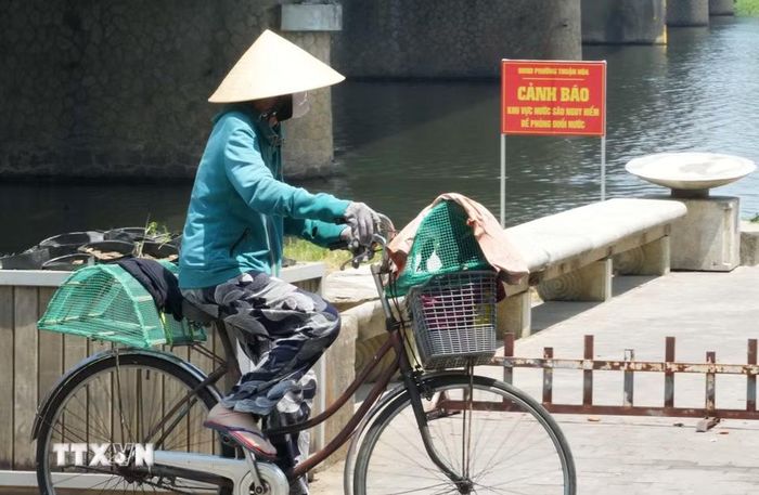 Người dân mặc kín đồ bảo hộ chống nắng nóng khi mưu sinh ở bờ Nam sông Hương, phường Thuận Hóa, thành phố Huế. (Ảnh: Nguyên Lý/TTXVN)