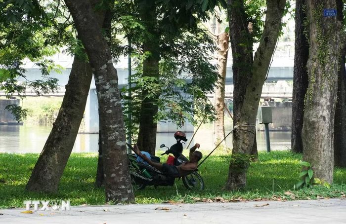 Người dân đến công viên ở bờ Bắc sông Hương, phường Phú Xuân, thành phố Huế, để hóng mát, tránh nắng nóng gay gắt. (Ảnh: Nguyên Lý/TTXVN)