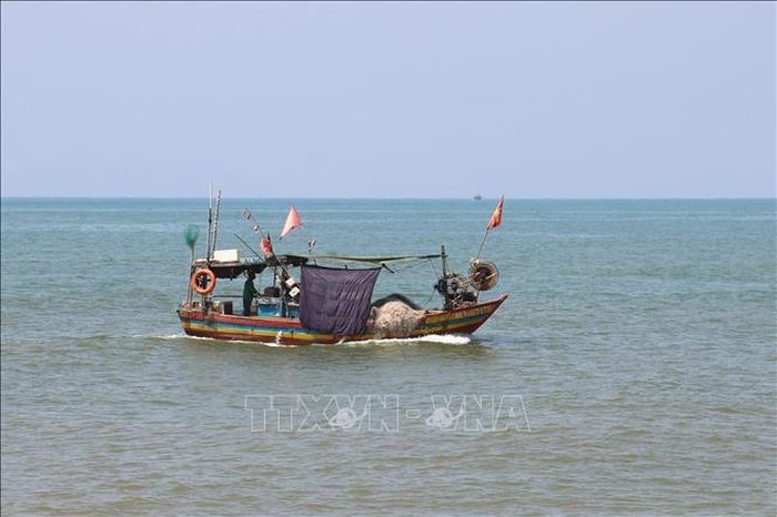Ngư dân xã Quỳnh Phú (tỉnh Nghệ An) căng những tấm vải che ánh nắng mặt trời chiếu rọi vào khu vực để hải sản trên khoang thuyền khi chạy vào cửa biển Lạch Quèn, vào khu neo đậu.