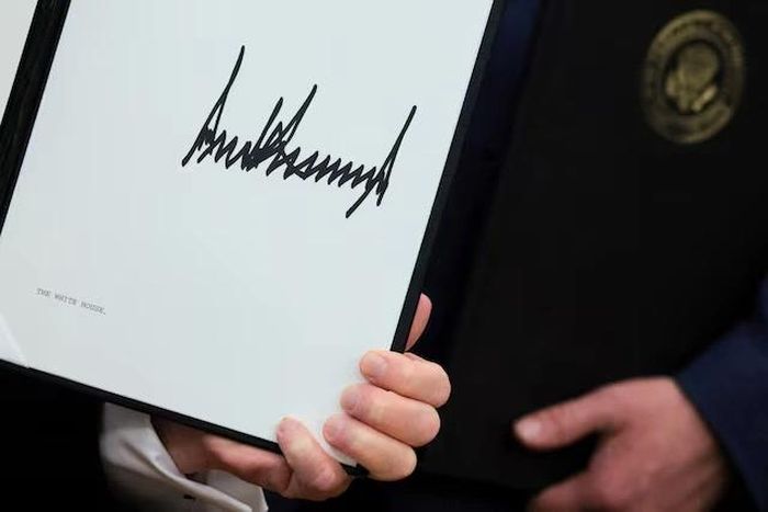 Tổng thống Mỹ Donald Trump cầm các sắc lệnh hành pháp sau khi ký tại Phòng Bầu dục ở Nhà Trắng, Washington D.C. Ảnh: Reuters.