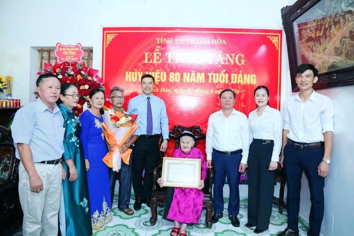 Phó Bí thư Thường trực Tỉnh ủy Nguyễn Hồng Phong trao tặng Huy hiệu 80 năm tuổi Đảng và tặng hoa chúc mừng đảng viên Vũ Thị Xâm.