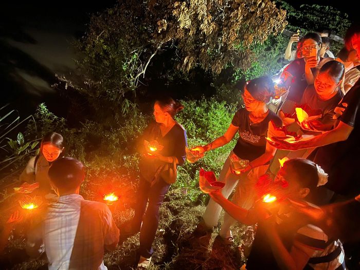 Người dân truyền tay nhau những ngọn nến hoa đăng thả xuống sông.