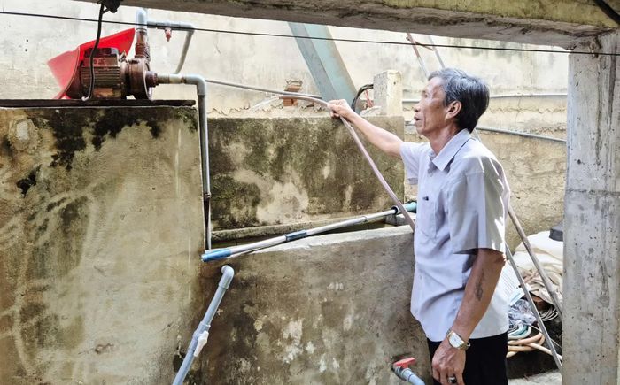 Ông Bùi Khảm bên hệ thống bể lọc thủ công do gia đình đầu tư để xử lý tạm thời nguồn nước nhiễm phèn phục vụ sinh hoạt - Ảnh: K.S