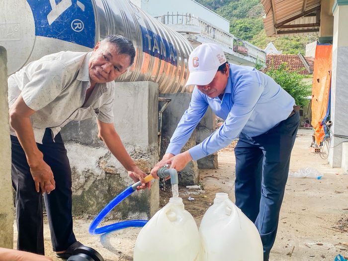 Chủ tịch UBND phường Quy Nhơn Nguyễn Đức Toàn (đội mũ) chia sẻ niềm vui với người dân Hải Minh khi nguồn nước sạch chính thức về với làng chài sau nhiều năm mong đợi.