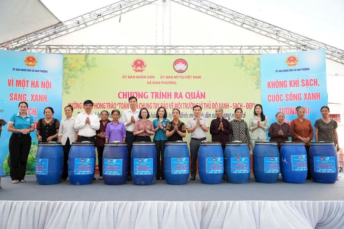 Lãnh đạo xã Đan Phượng tặng thùng xử lý rác hữu cơ cho các hộ dân. Ảnh: PV