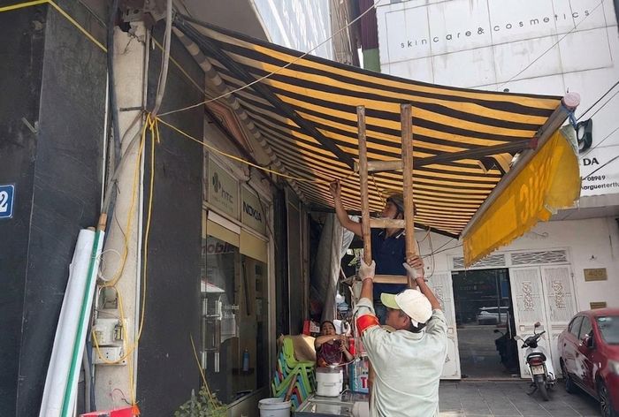 Lực lượng chức năng xã Hoài Đức thực hiện tháo dỡ mái che, mái vẩy trên các tuyến đường. Ảnh: HĐ