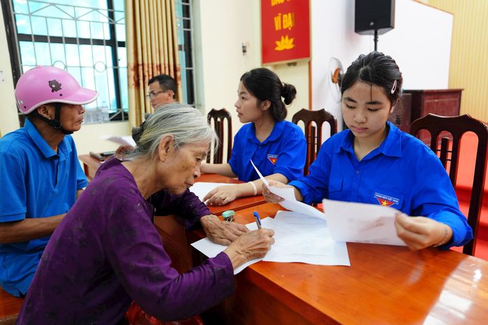 Đoàn thanh niên xã Vân Đình (Hà Nội) hỗ trợ người cao tuổi thực hiện thủ tục chi trả lương hưu qua tài khoản ngân hàng. Ảnh: Lại Tấn