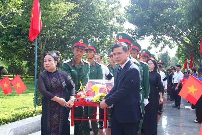 Bà Cao Thị Hòa An và ông Đỗ Hữu Huy thực hiện nghi thức di chuyển hài cốt liệt sĩ vào vị trí an táng. (Ảnh: Thế Hùng)