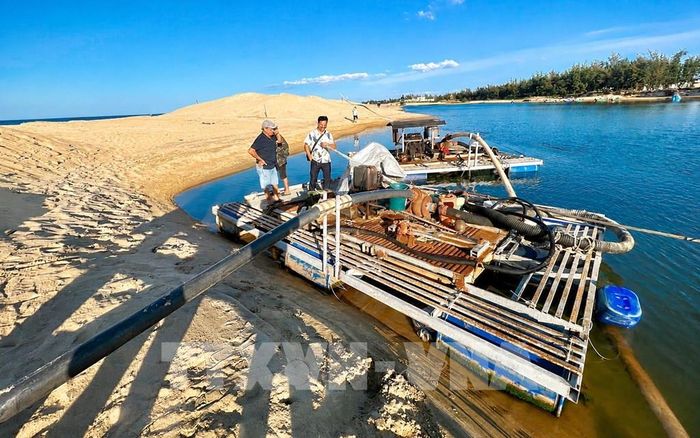 Chính quyền xã Đông Trạch, tỉnh Quảng Trị huy động lực lượng và phương tiện nạo vét, mở tuyến luồng tạm xuyên qua cồn cát tại cửa biển Lý Hòa nhằm khơi thông dòng chảy, tạo điều kiện cho tàu thuyền ra vào và tăng khả năng tiêu thoát nước. Ảnh: Nguyên Linh - TTXVN
