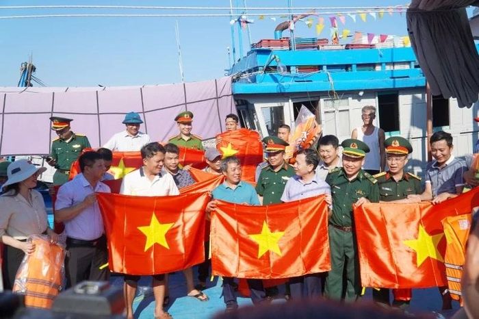 Ban tổ chức trao tặng cờ Tổ quốc, áo phao cho ngư dân.