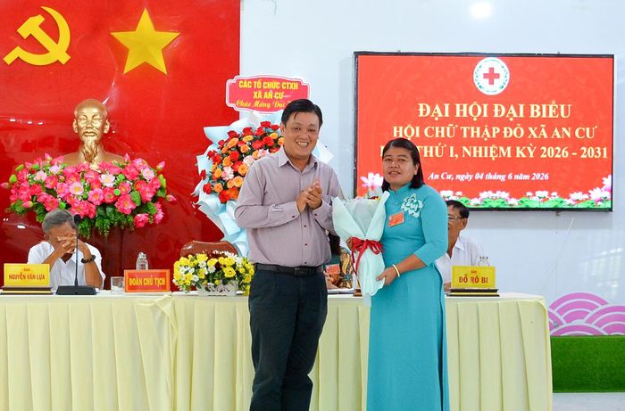 Chủ tịch UBND xã An Cư Nguyễn Duy Phong tặng hoa chúc mừng Chủ tịch danh dự Hội Chữ thập đỏ xã An Cư Neáng Sêm.