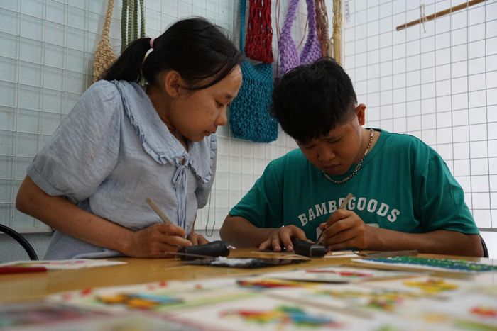 Chị Hồ Thị Láng hướng dẫn làm tranh giấy xoắn, góp phần tạo thêm cơ hội sinh kế cho người khuyết tật. Ảnh: HỮU TRUNG - TRÂM ANH