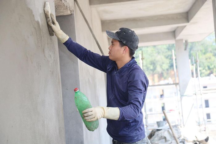 Thợ xây Nguyễn Văn Tâm đang cẩn thận với công việc trát những bức tường hạng mục nhà lớp học.