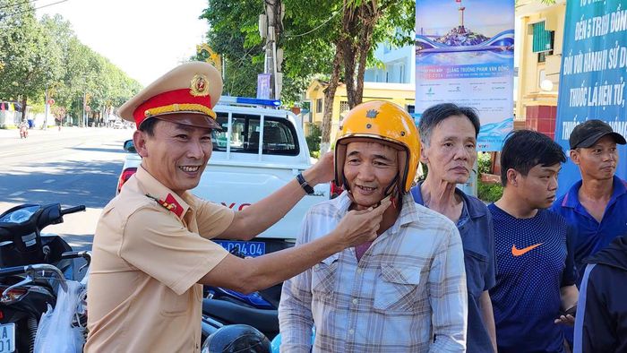 Lãnh đạo Phòng CSGT Công an tỉnh Quảng Ngãi trực tiếp hướng dẫn người dân cách đội nón bảo hiểm đúng cách.