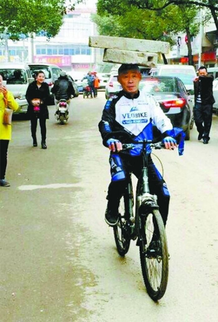 Ông Trương Huân Mộc vừa đội cối đá trên đầu, vừa đạp xe