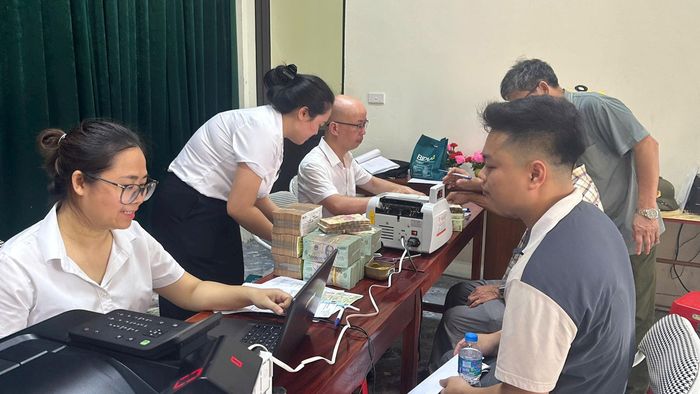 Người dân thôn Định Quán nhận tiền chi trả, bồi thường GPMB dự án đầu tư xây dựng Khu đô thị thể thao Quốc tế Hà Nội ngày 4-6. Ảnh: PV