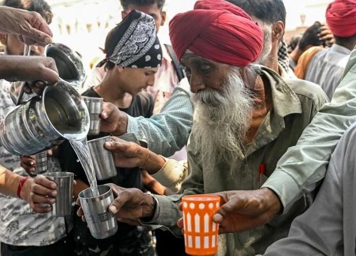 Tình nguyện viên rót nước đường cho người dân chống nóng ở Amritsar, Ấn Độ. Ảnh: AFP