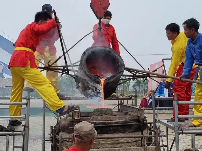 Nghệ nhân Lê Văn Dương (phải) cùng con trai và thợ trong làng nghề Trà Đông đổ đồng nấu chảy vào khuôn. Ảnh: Xuân Cường