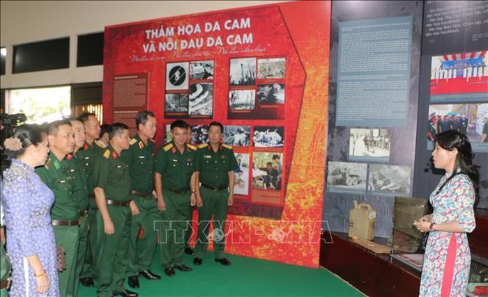 Đại biểu tham quan và nghe thuyết minh hình ảnh, hiện vật Triển lãm “Hồi sinh những vùng đất chết”.
