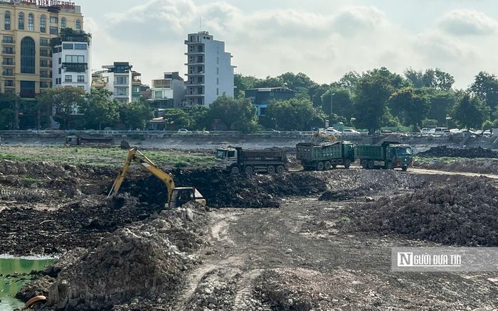 Bên trong, hàng loạt máy móc đang tiến hành nạo vét lòng hồ. Hàng loạt xe tải nối đuôi nhau chở bùn đất ra khỏi công trường.
